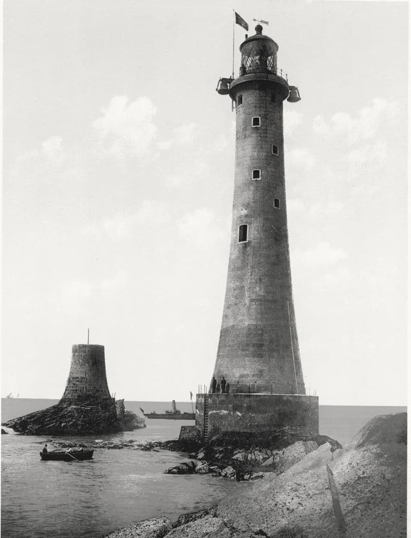 Eddystone Lighthouse standing in the open sea beside the stub of its predecessor, a rowboat below.